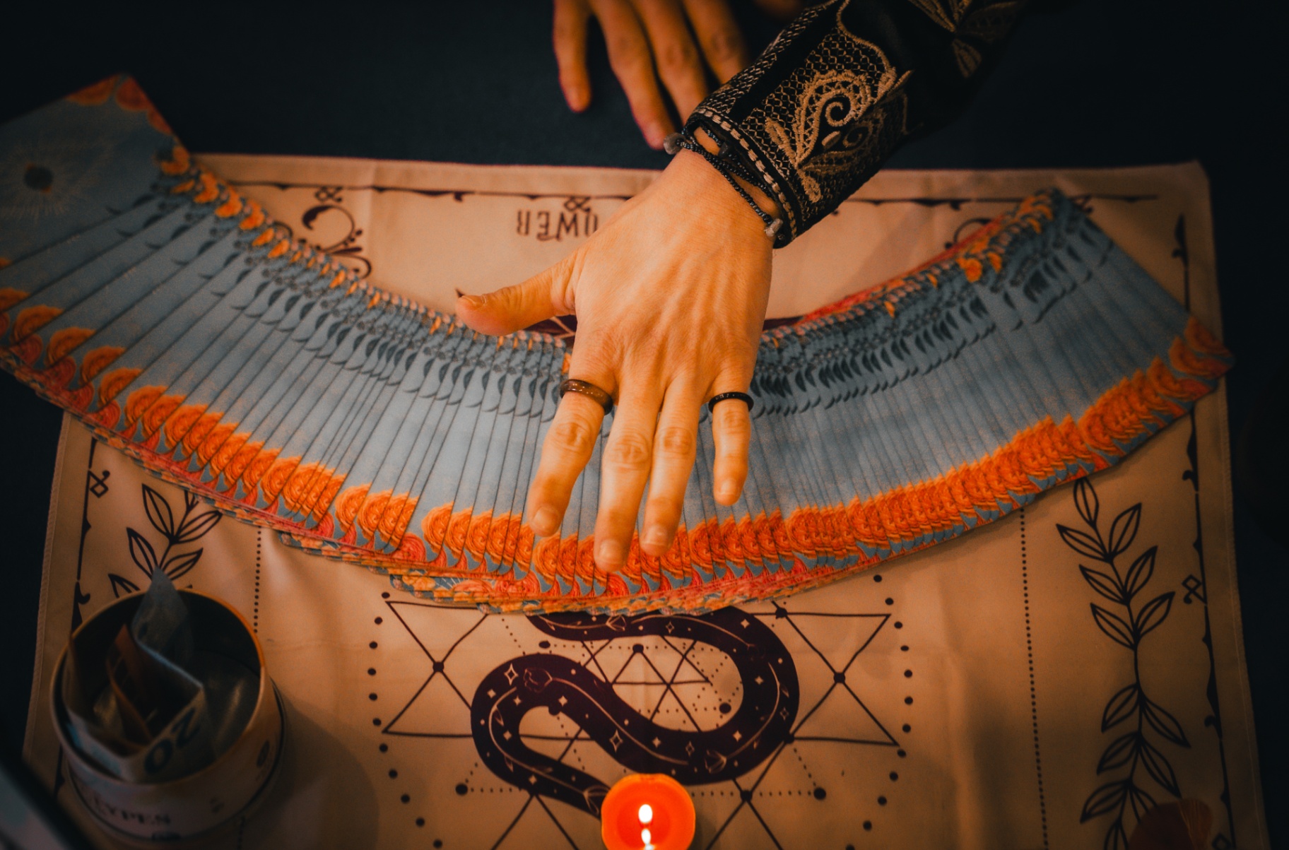 Tarot cards, rune stones and candle on deep teal velvet